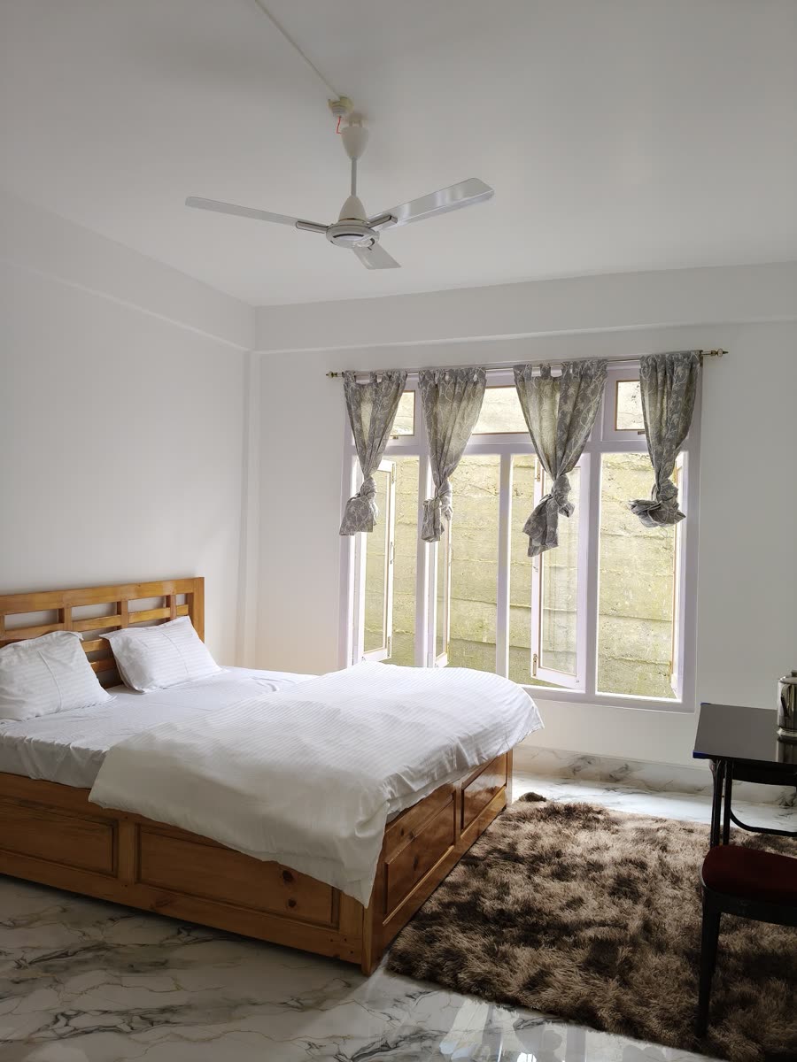 Spacious guest room with wooden double bed and large window at Gonpapa Homestay