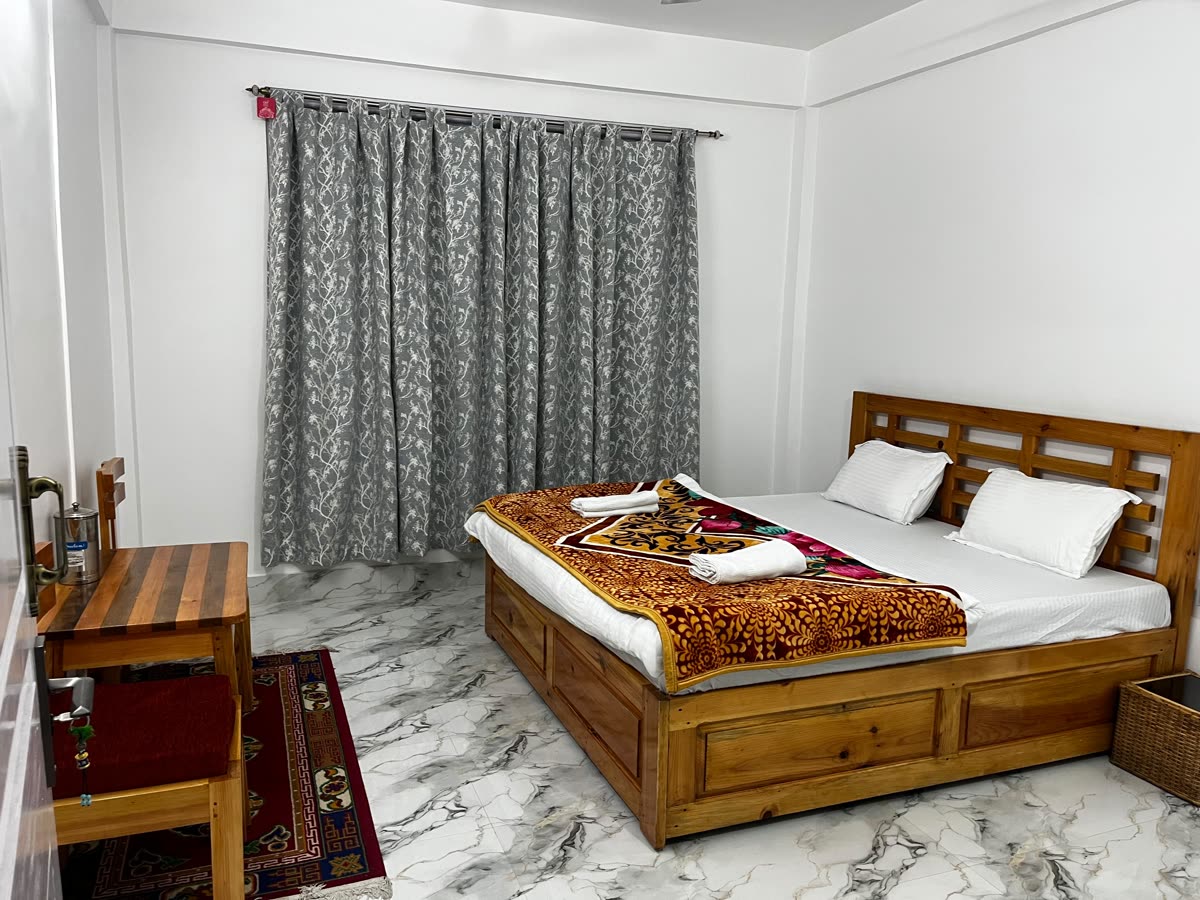 Clean double-bed room with wooden furniture and rug at Gonpapa Homestay